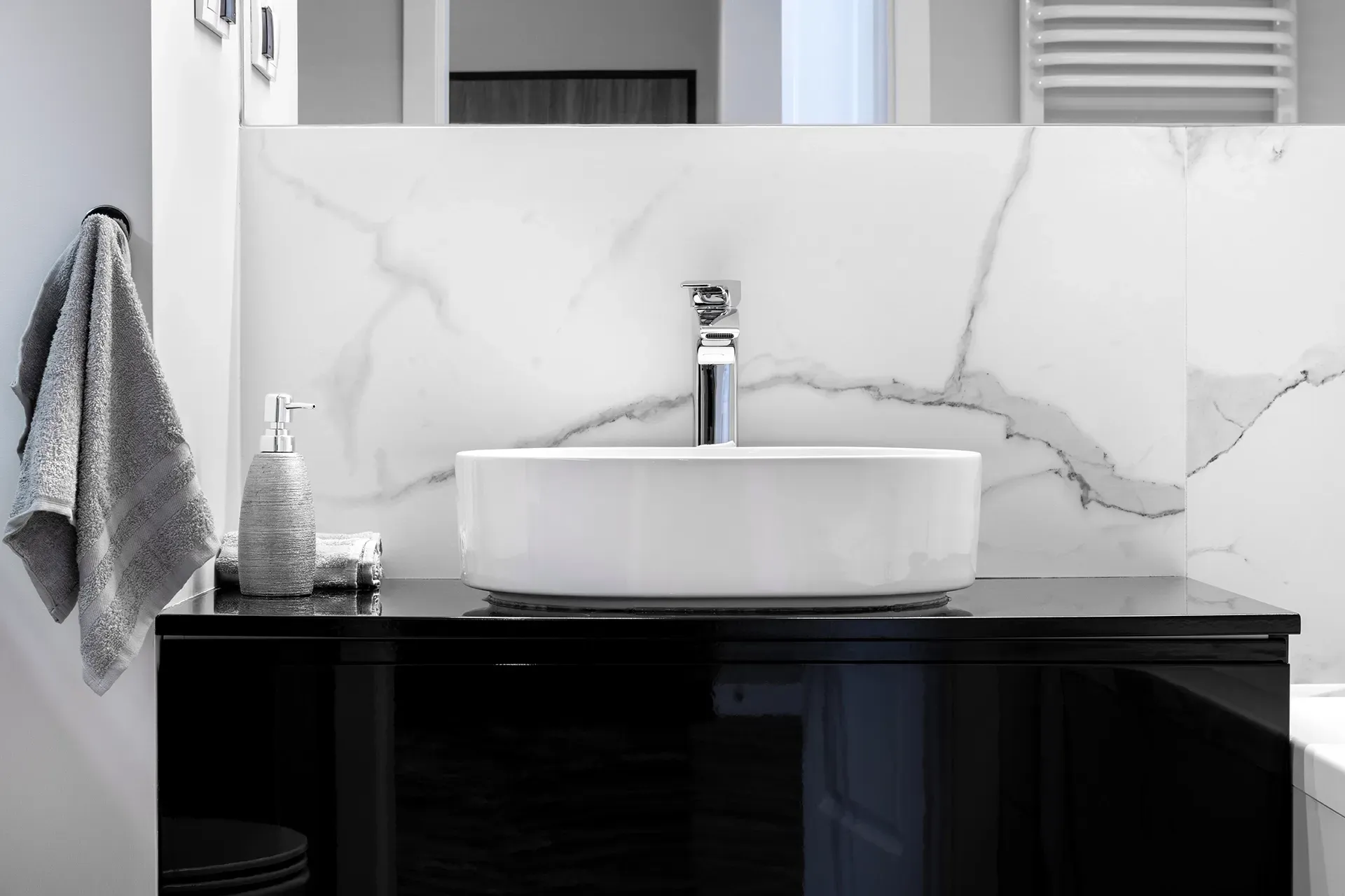 A bathroom with a sink , mirror and towel rack.