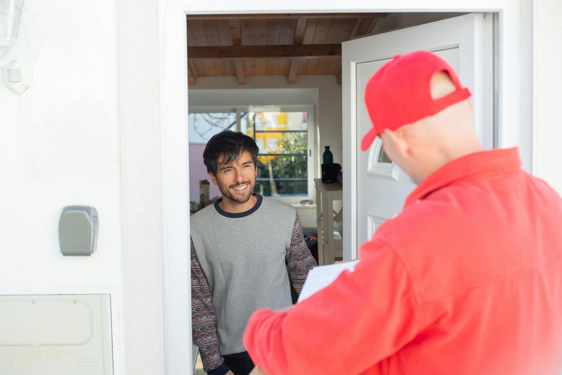 A plumbing employee man is welcomed by a man in his doorway.