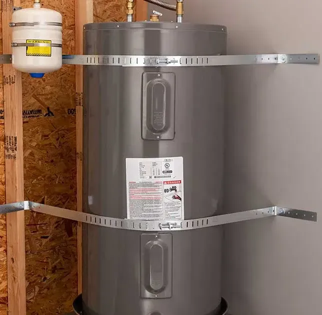 Water heater secured to wall with metal straps. Expansion tank to the left.