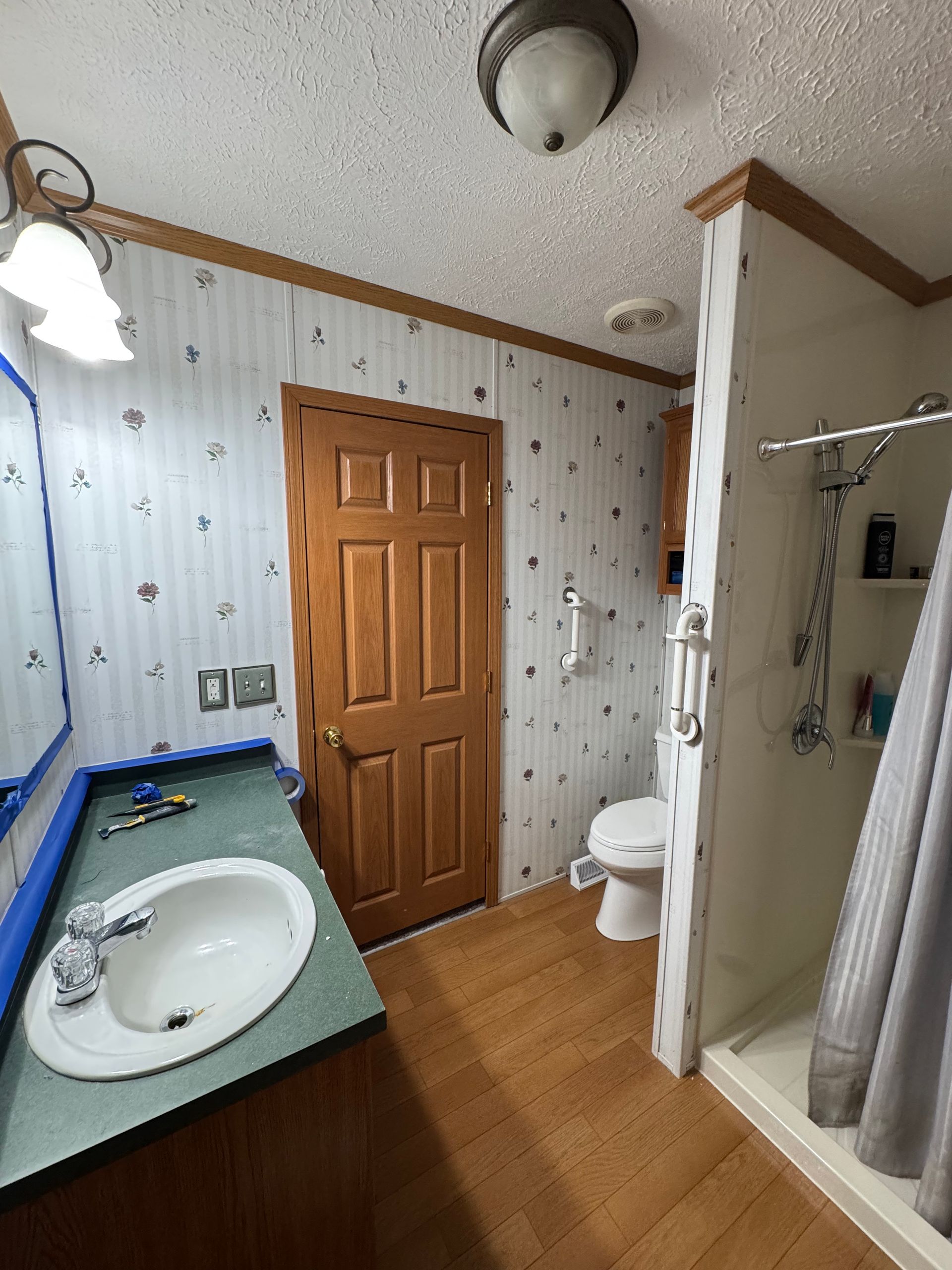 Bathroom with sink counter, wooden door, toilet, and shower curtain in a small tiled room