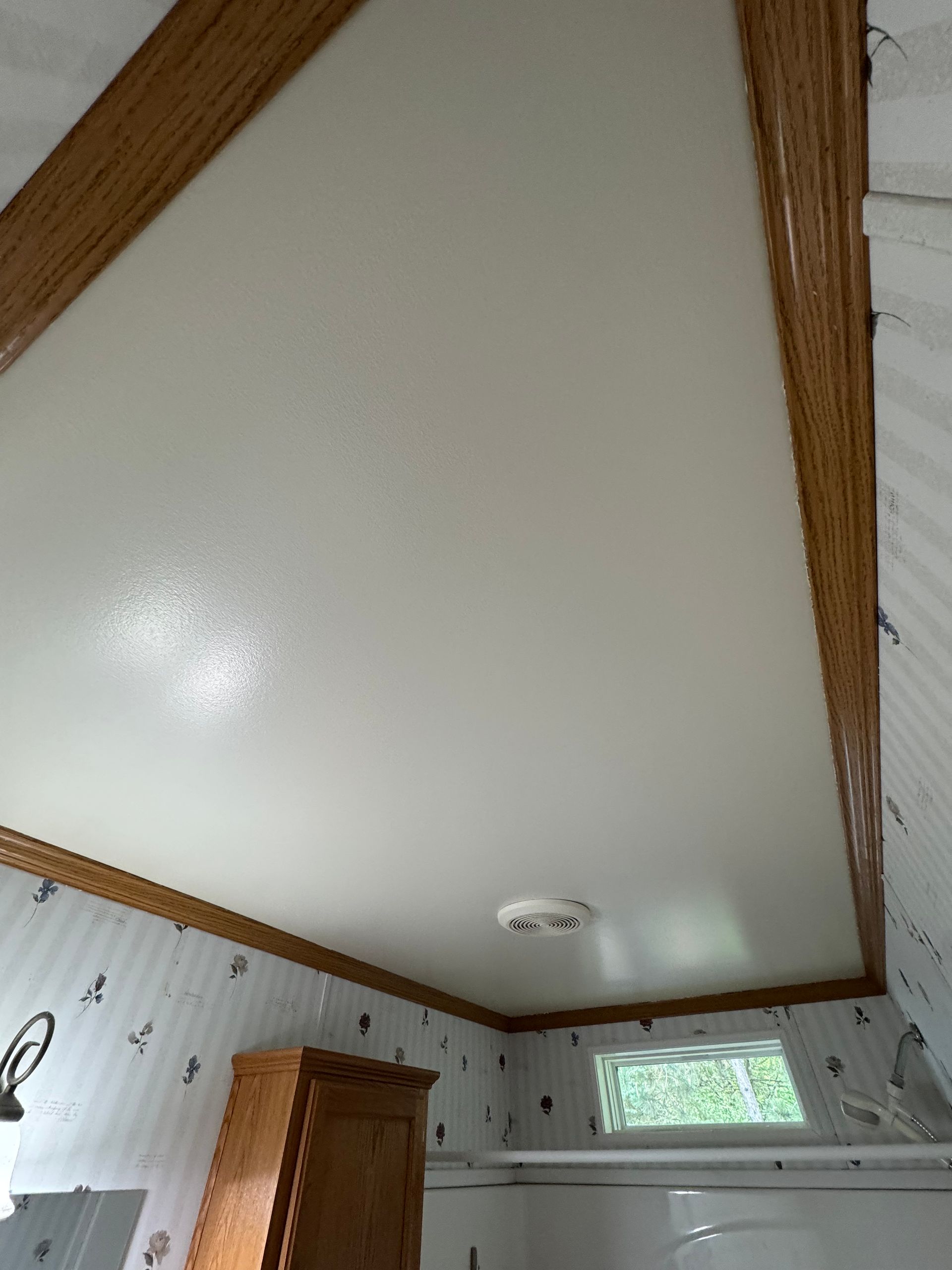 White vaulted ceiling with wood beams and a small skylight in a bedroom or attic room
