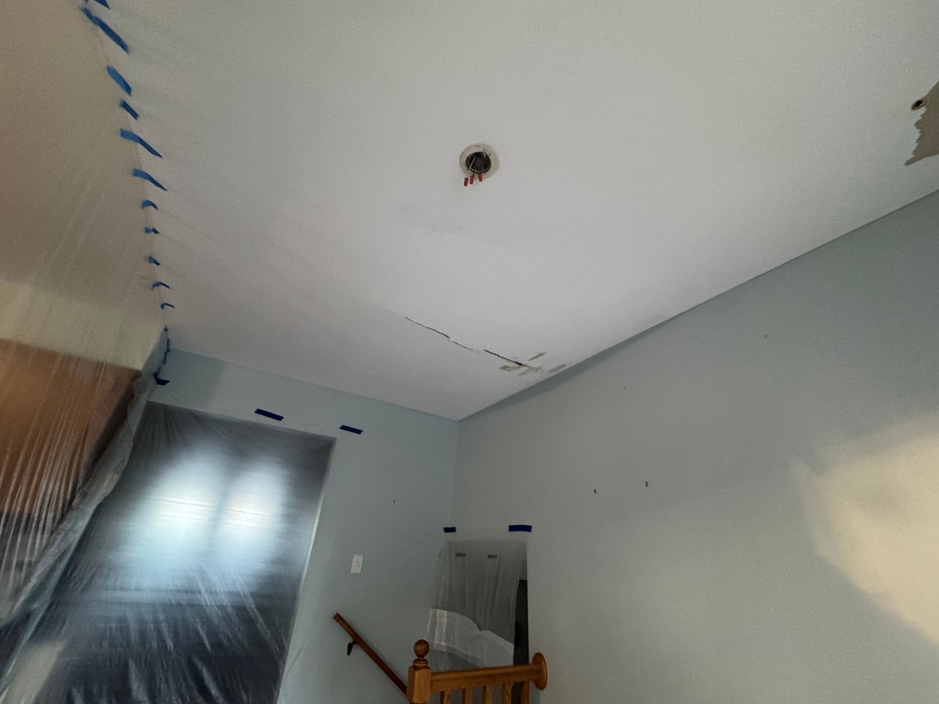 Empty room under renovation with taped ceiling seams, a light gray wall, and a door opening.