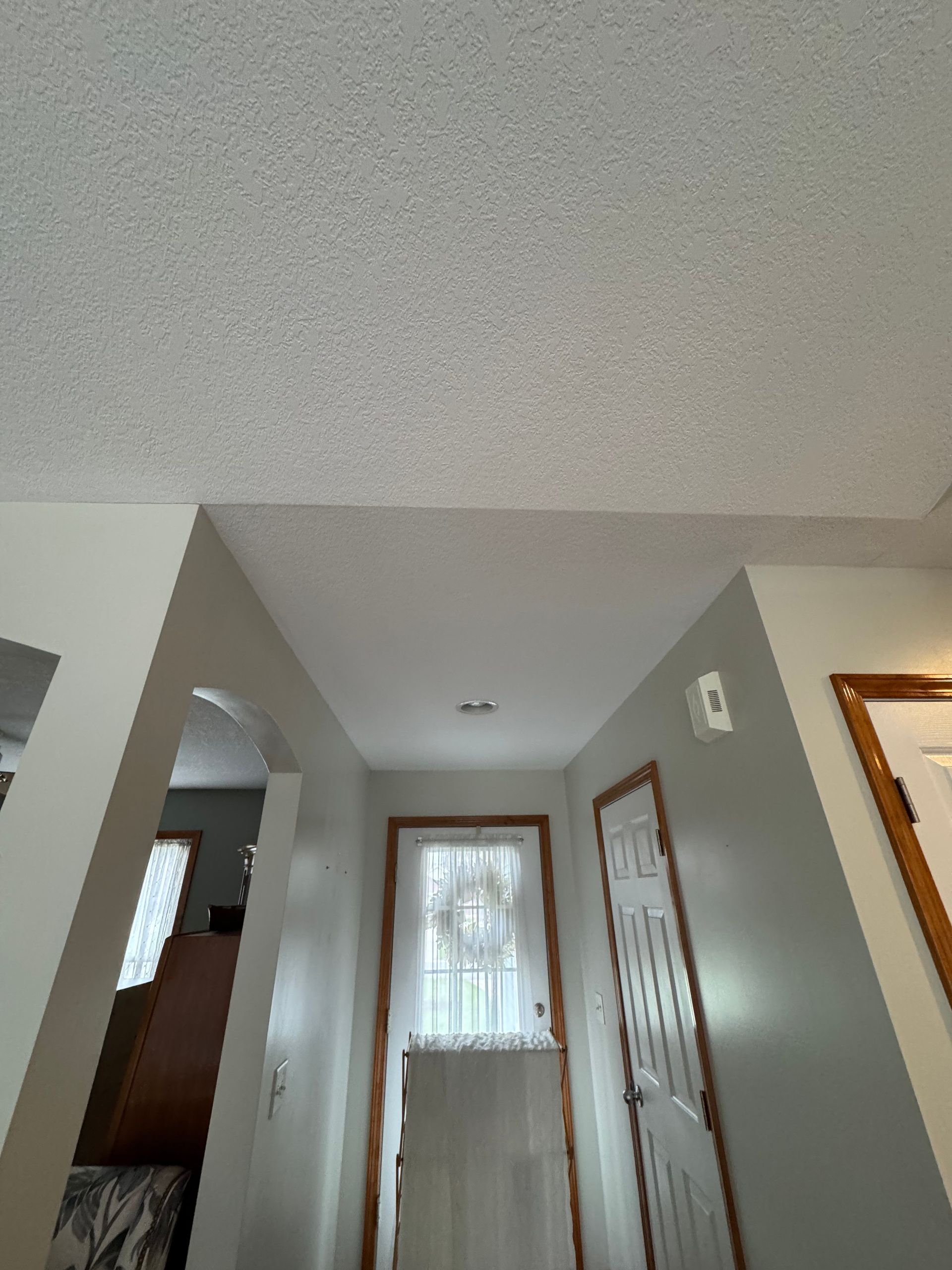 Interior hallway with gray walls, white trim, and doors, viewed toward a window at the end.