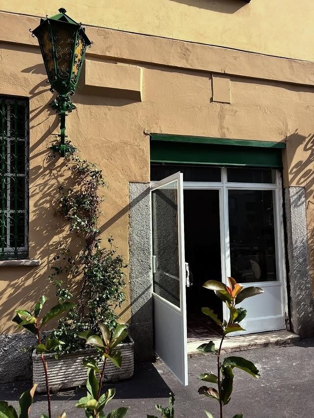 Porta esterna bianca aperta, sotto una tenda da sole verde. 