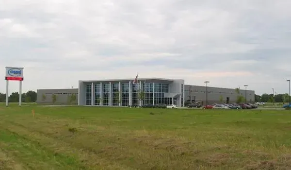 Modern glass-fronted building on a grassy field under a cloudy sky