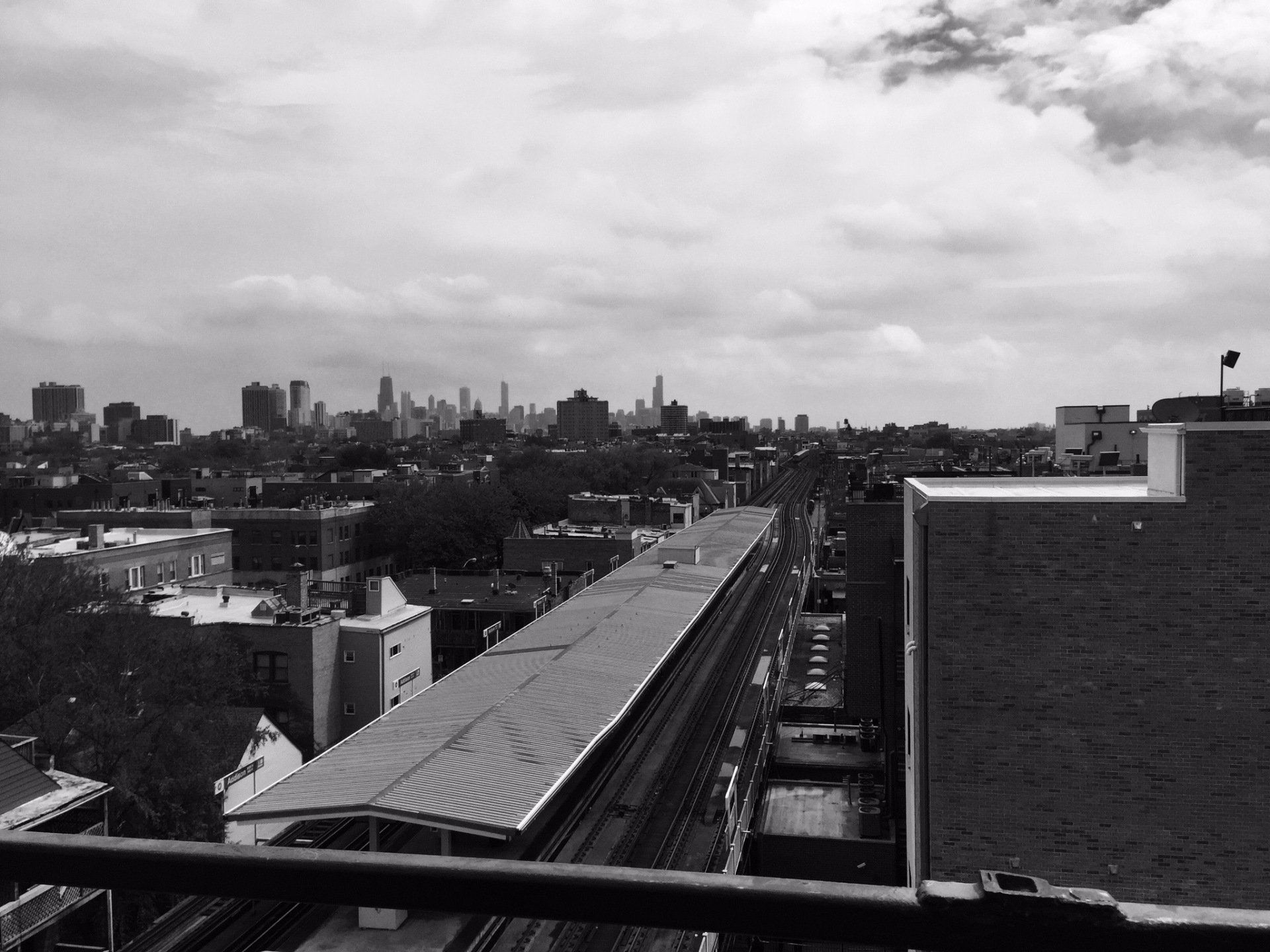 A black and white photo of a city with a train track in the foreground