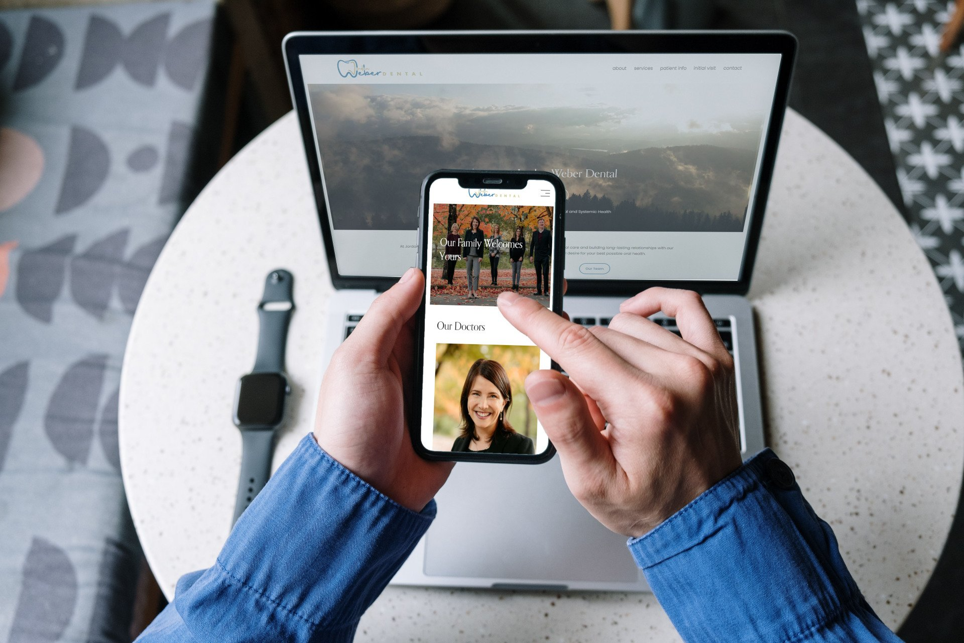 A person is holding a cell phone in front of a laptop computer.