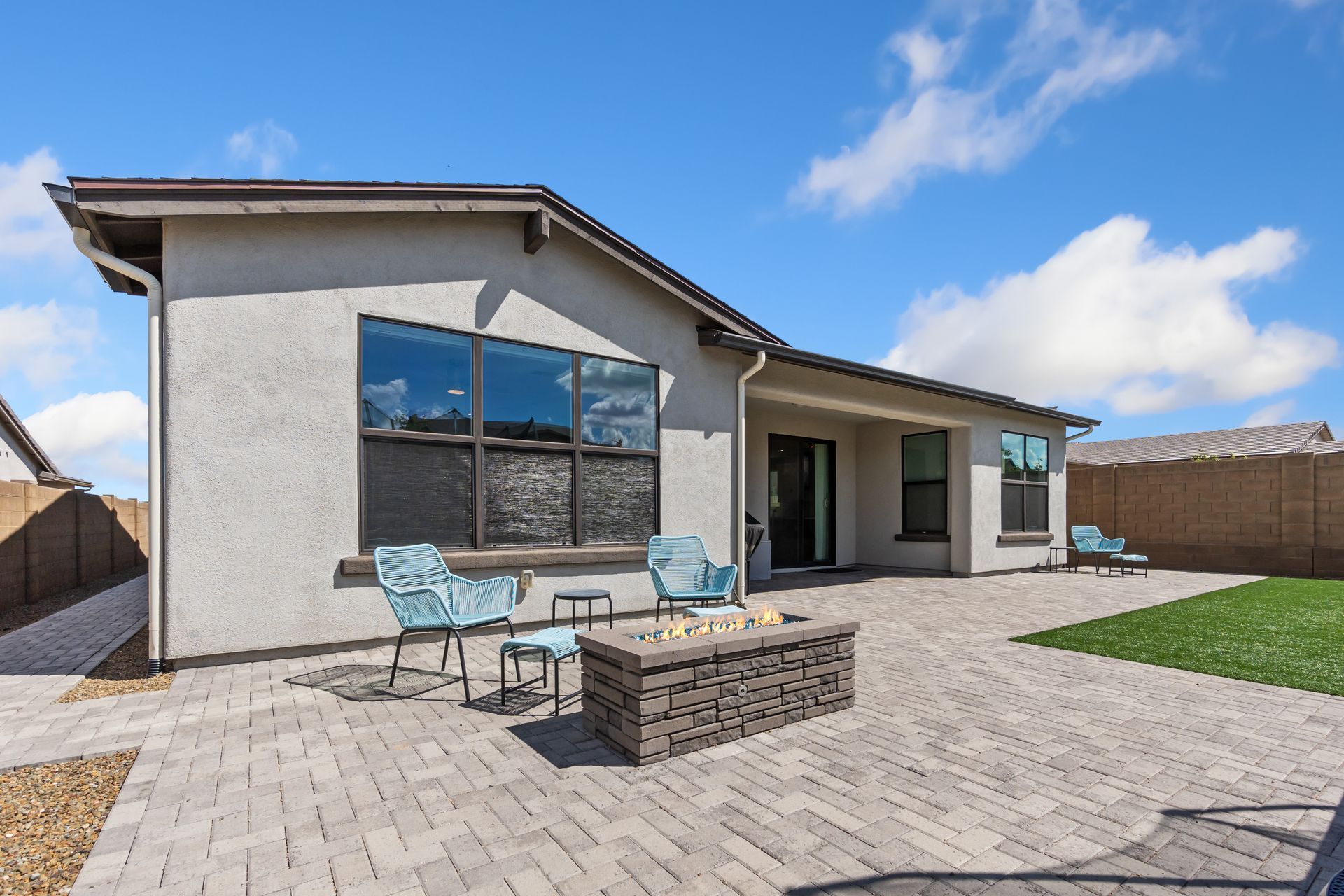 Backyard patio with outdoor seating, fire pit, and a modern house exterior with sliding glass doors