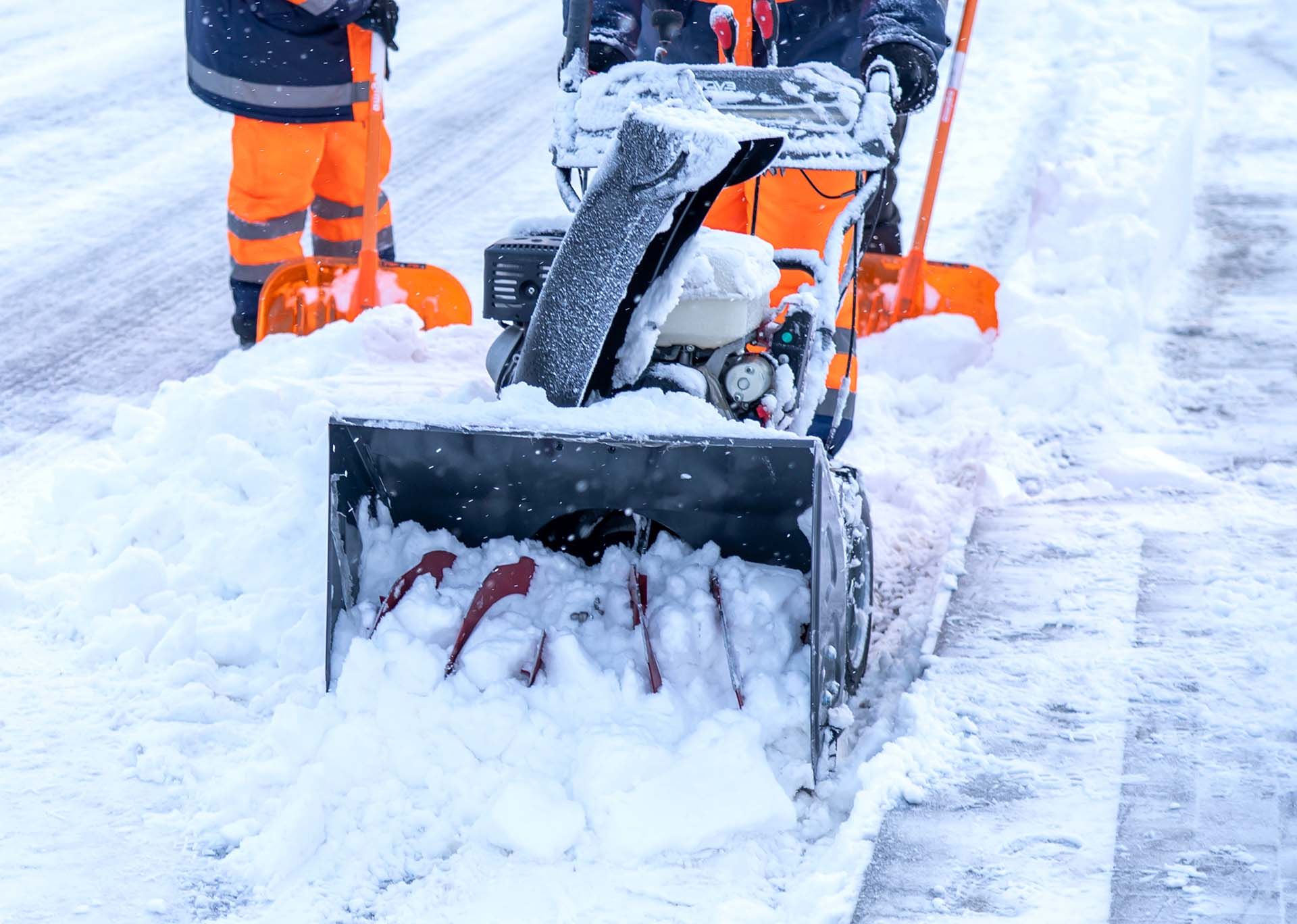 Person shoveling snow with an orange snowblower on a snowy street Person shoveling snow with an orange snowblower on a snowy street