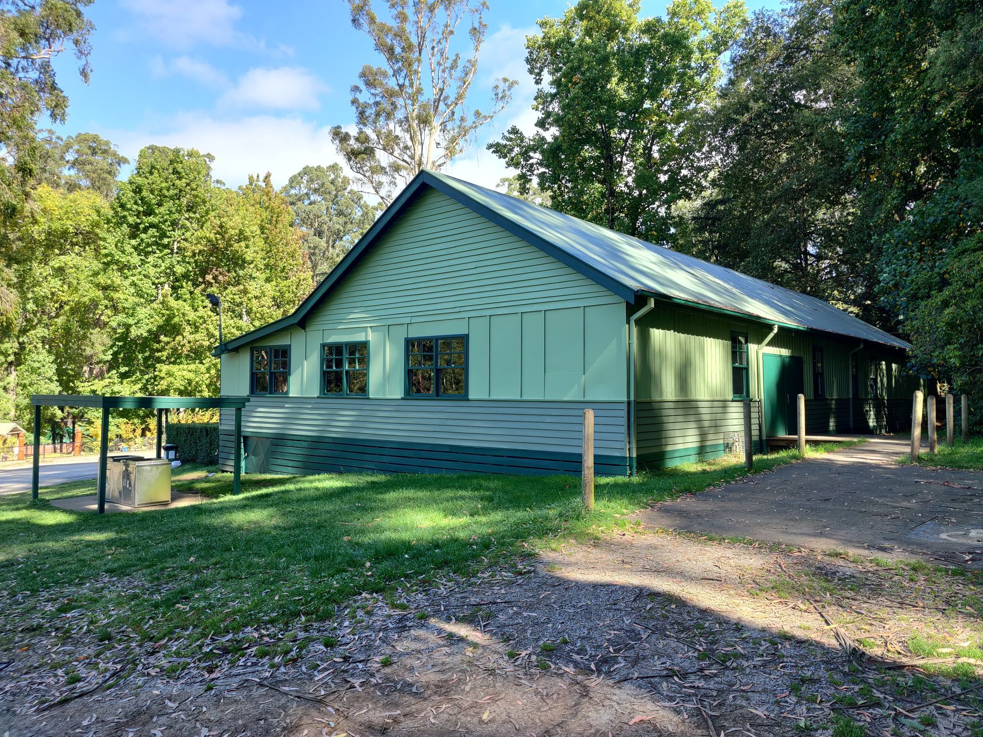 a green house with a green roof is surrounded by trees and grass .
