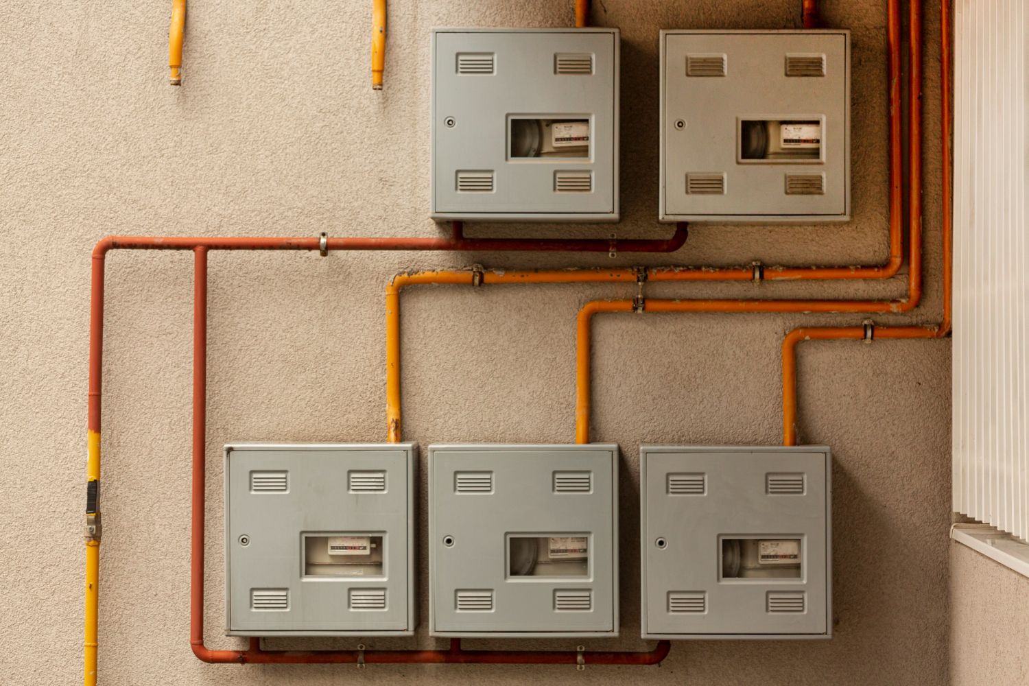 A close up of a wall with electrical boxes and pipes.