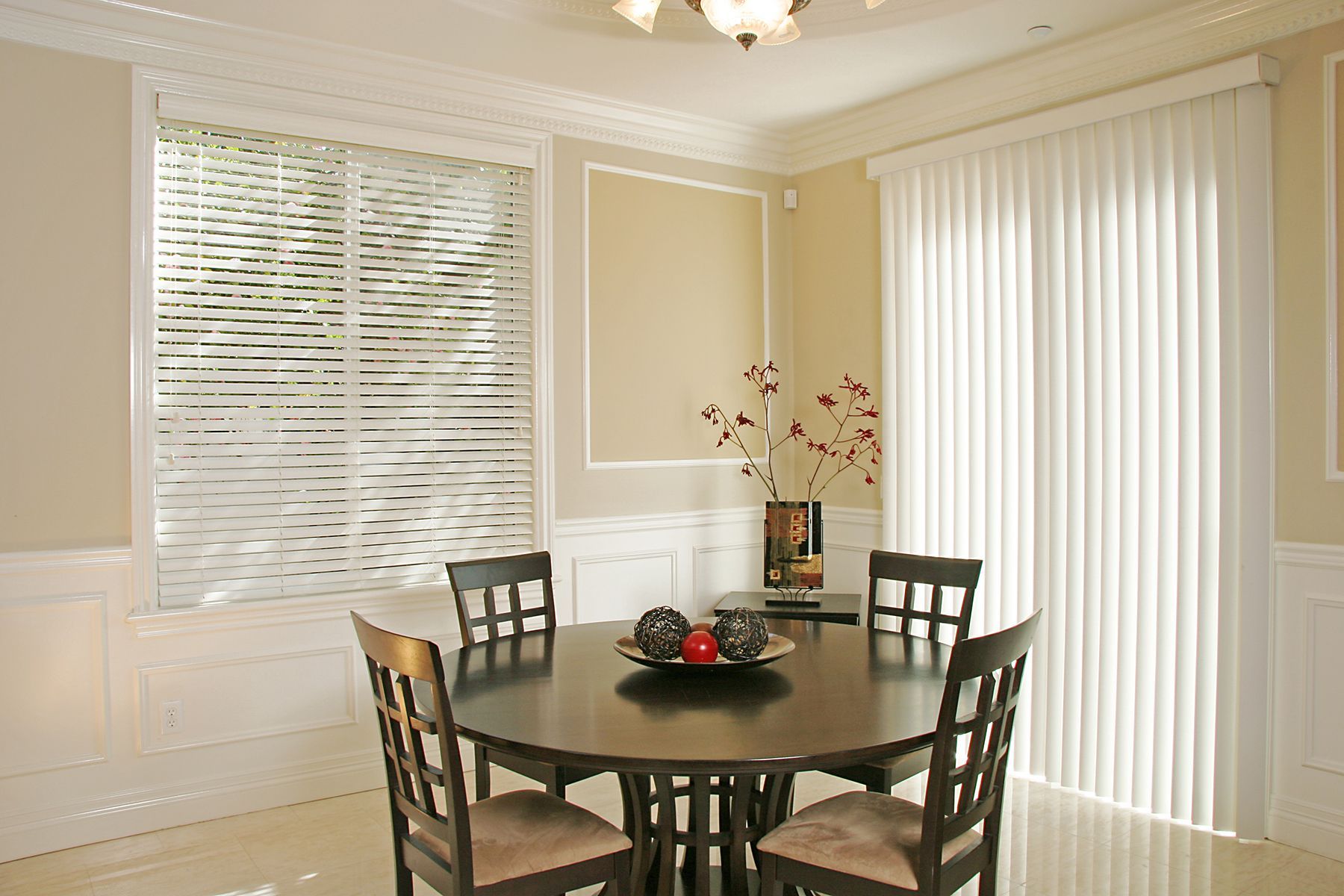 Dining room with a round table, four chairs, window blinds, and vertical blinds on the sliding door.