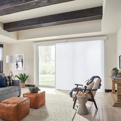 Living room with large white sliding blinds, exposed wooden beams, and beige walls.