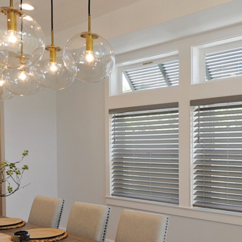Dining room with globe pendant lights, gray blinds, and a set table.