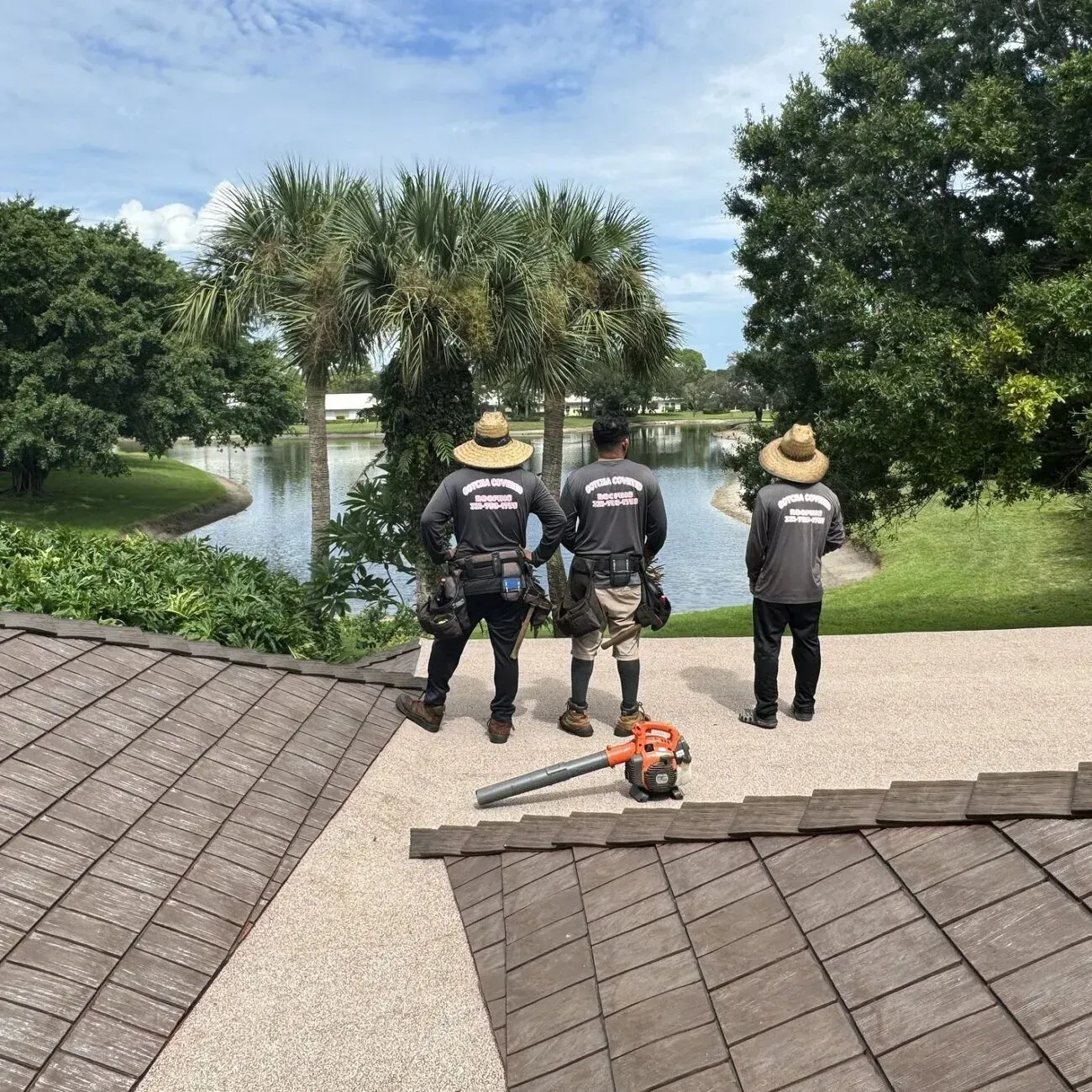 Three men are standing on a roof looking at a lake.