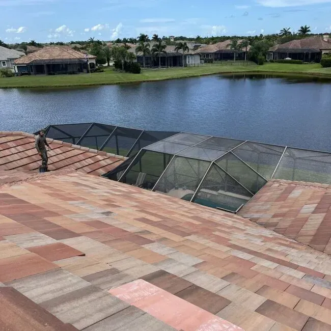 A man is standing on the roof of a house overlooking a lake.