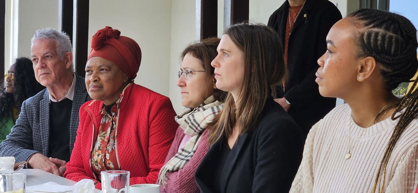 A crowd of people look off to the left, as if listening intently to someone talking.
