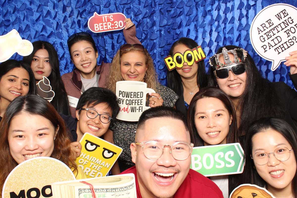 Group of people smiling, posing with props at a photo booth.