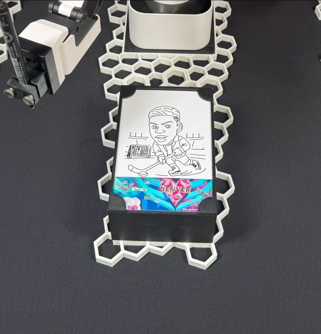 A card with a black and white portrait, resting on a white honeycomb-shaped holder, with a black and blue design beneath it.