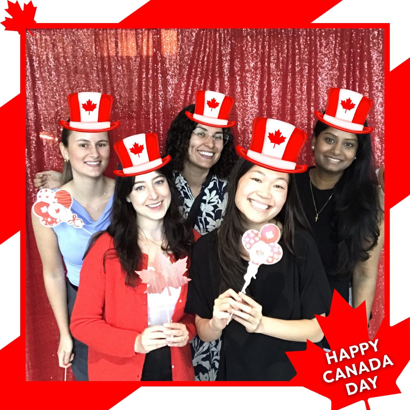 Five smiling women with Canada Day hats, posing in front of a red sequin backdrop.