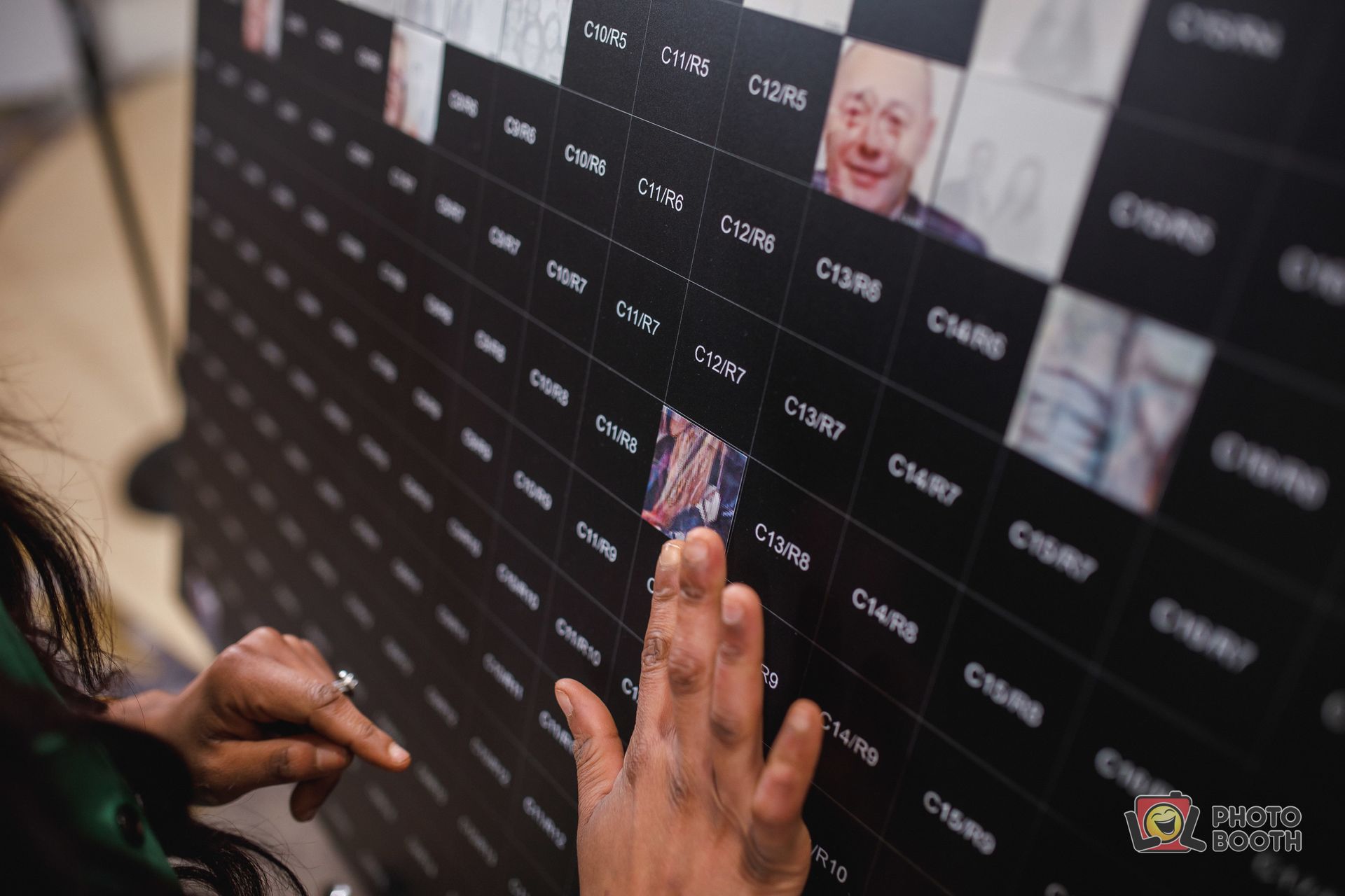 Person touching a grid display with images and text labels. Black background.