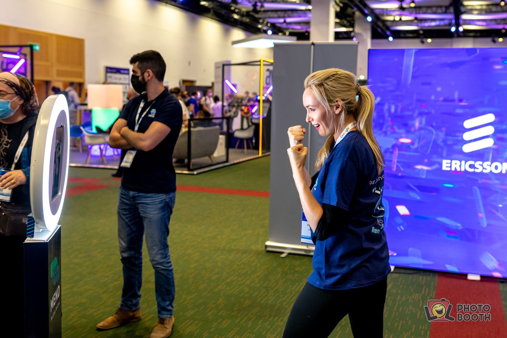Woman with arms raised and smiling, posing by a photo booth at an Ericsson event.