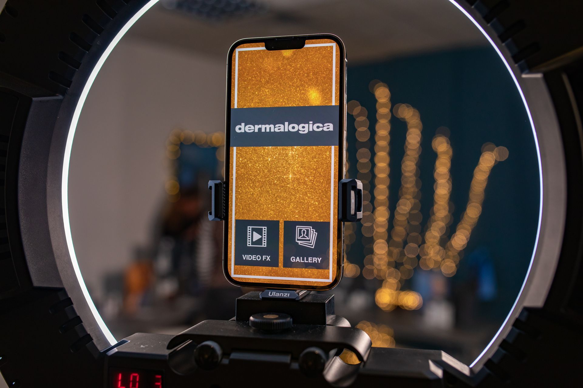 Smartphone with Dermalogica app displayed in a ring light. Gold glitter background.