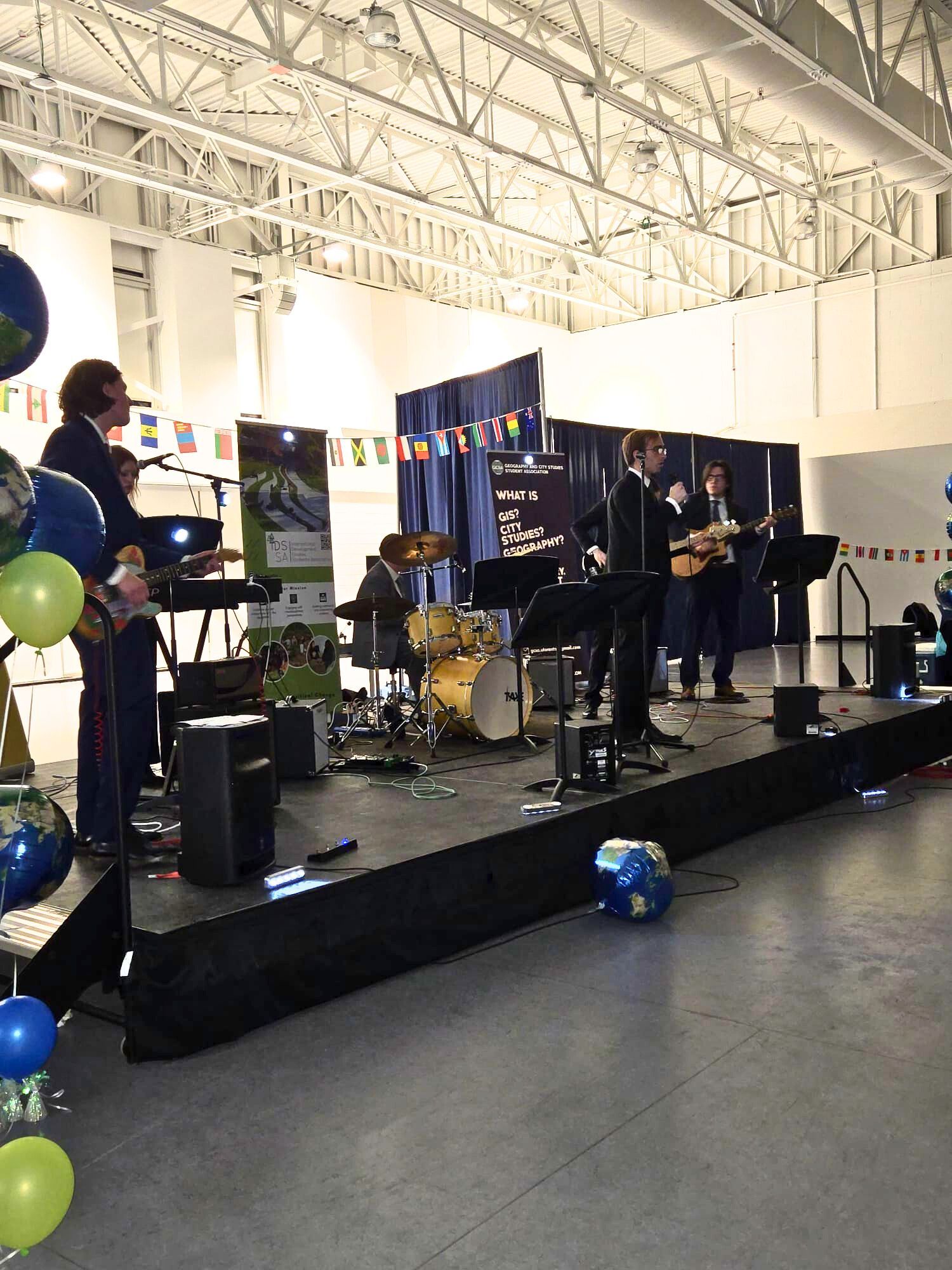 A band is playing on a stage with balloons in the background