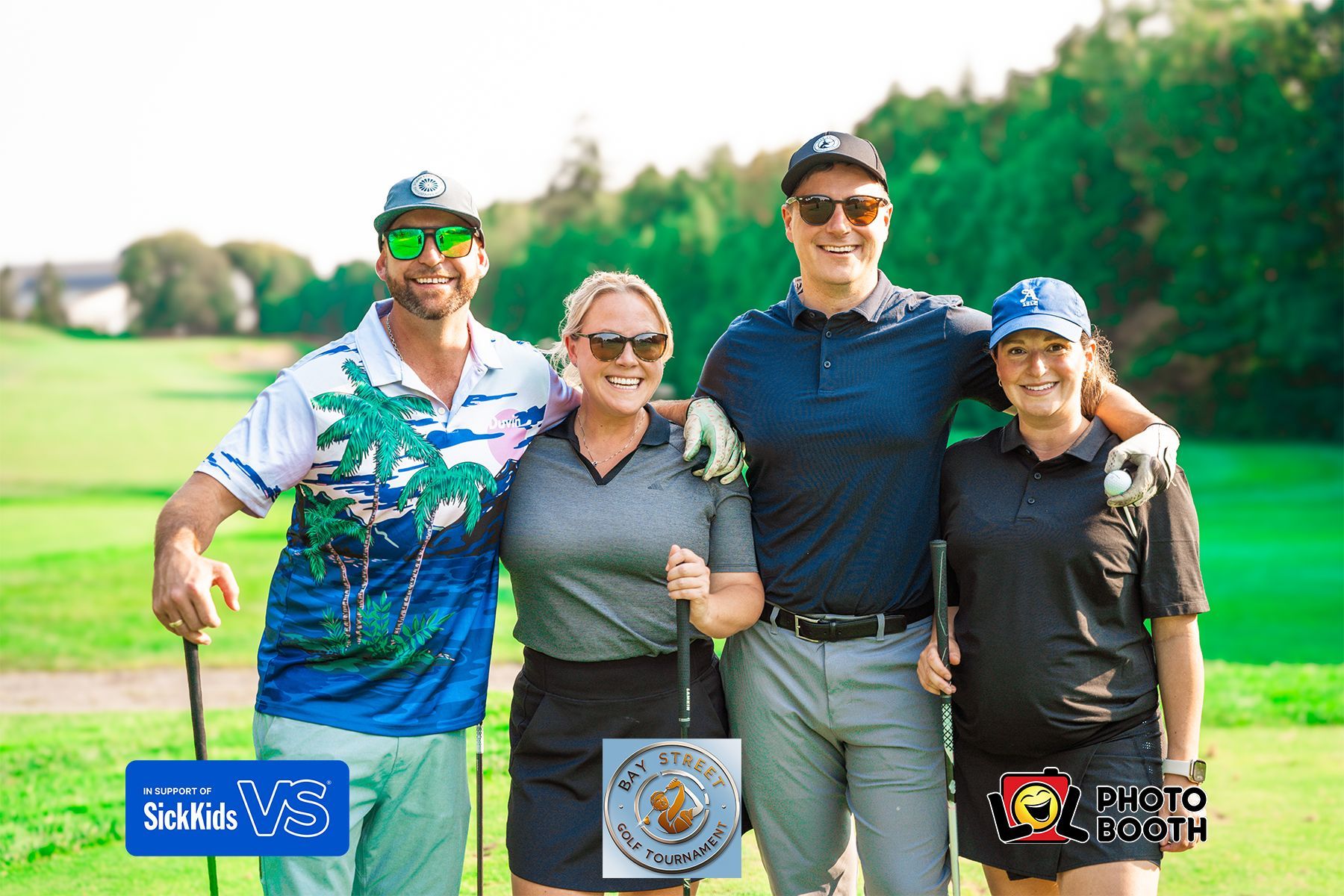 Four people smiling, holding golf clubs on a green. Sunny day.