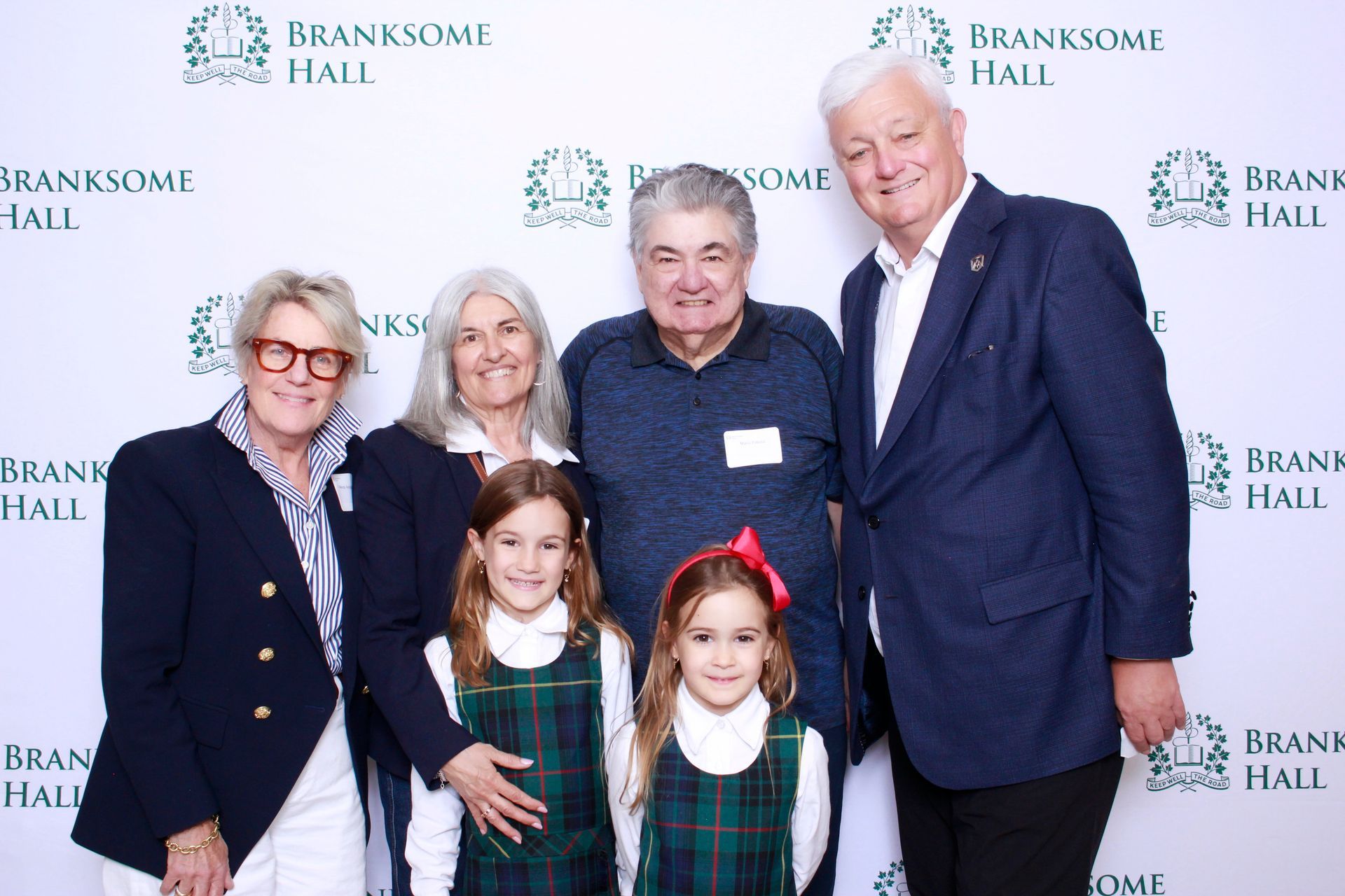 Group photo at Branksome Hall school event; two young girls in school uniforms flank adults in formal attire.