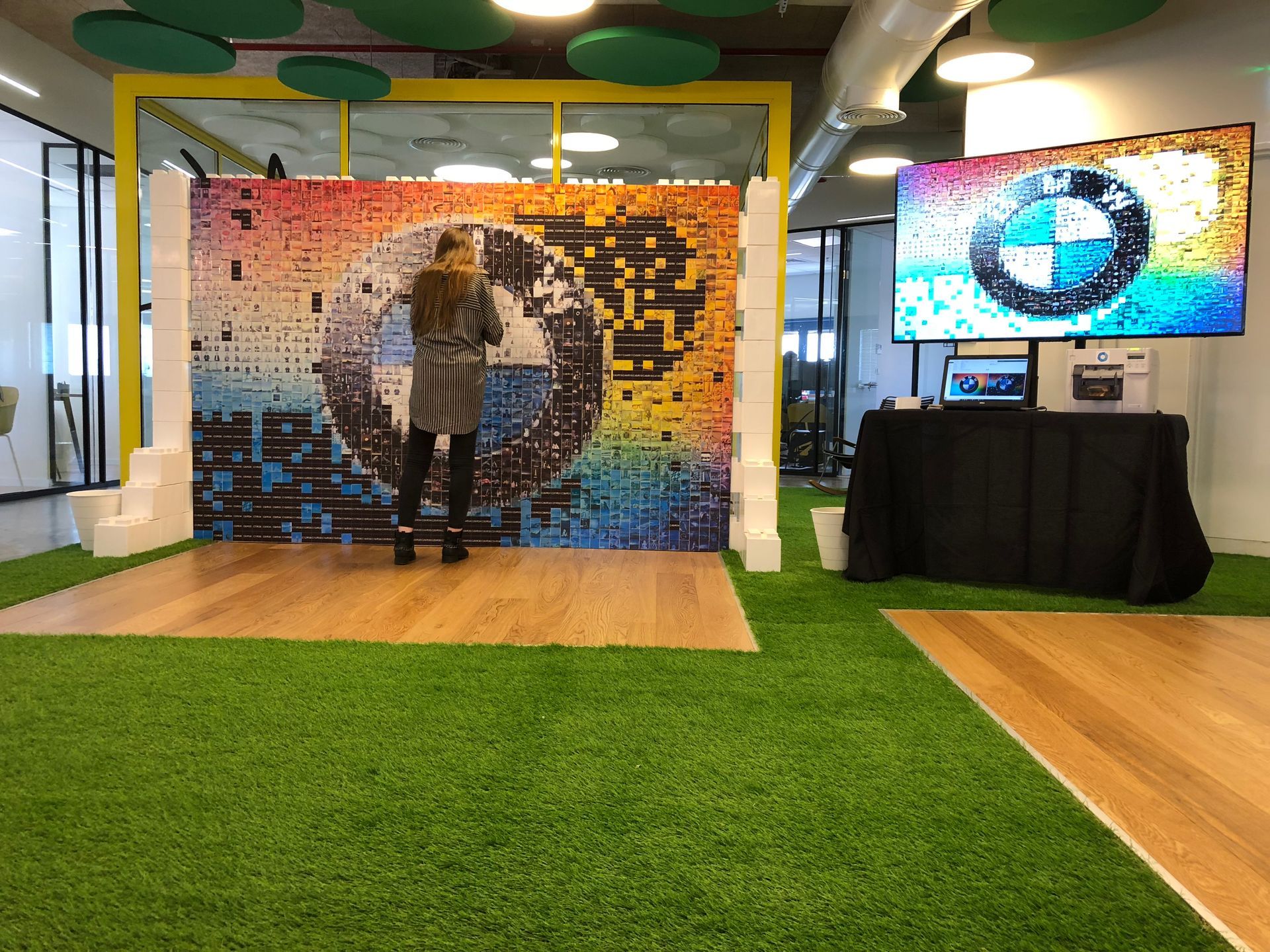 Woman standing in front of a colorful BMW logo mosaic stage, a large screen displays the logo.