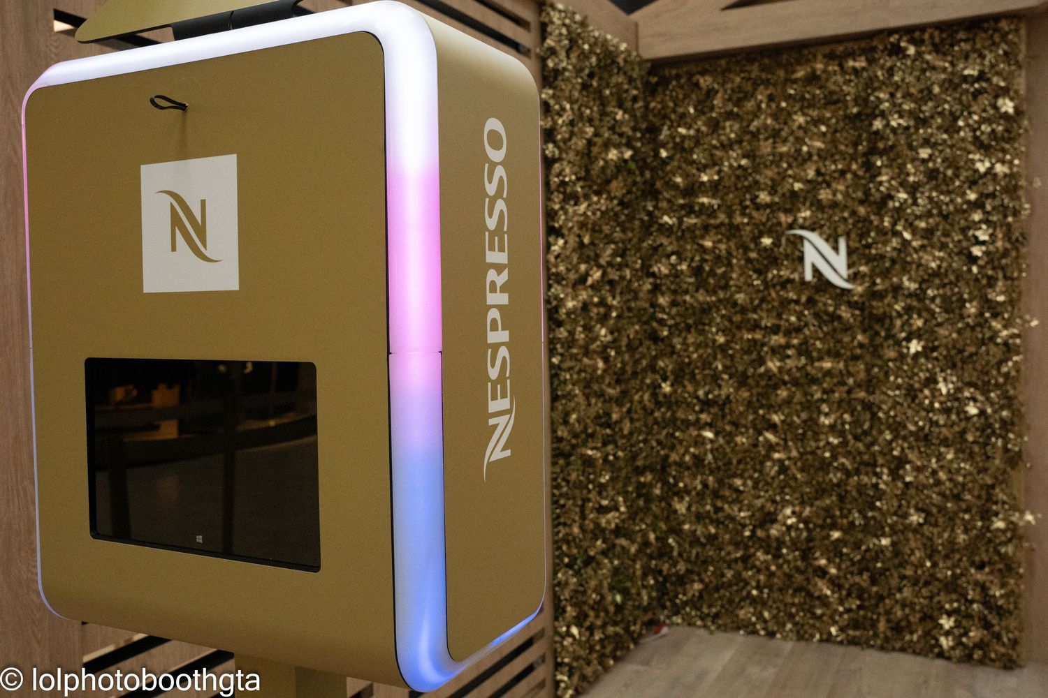 Nespresso-branded photo booth with a gold facade, next to a gold leaf backdrop.