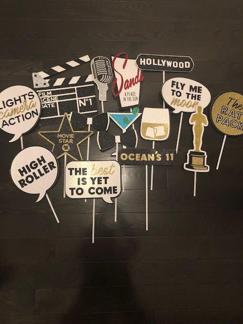 Photo booth props on sticks: clapperboard, Hollywood sign, speech bubbles, martini, mic, Oscar statue, whiskey, stars.