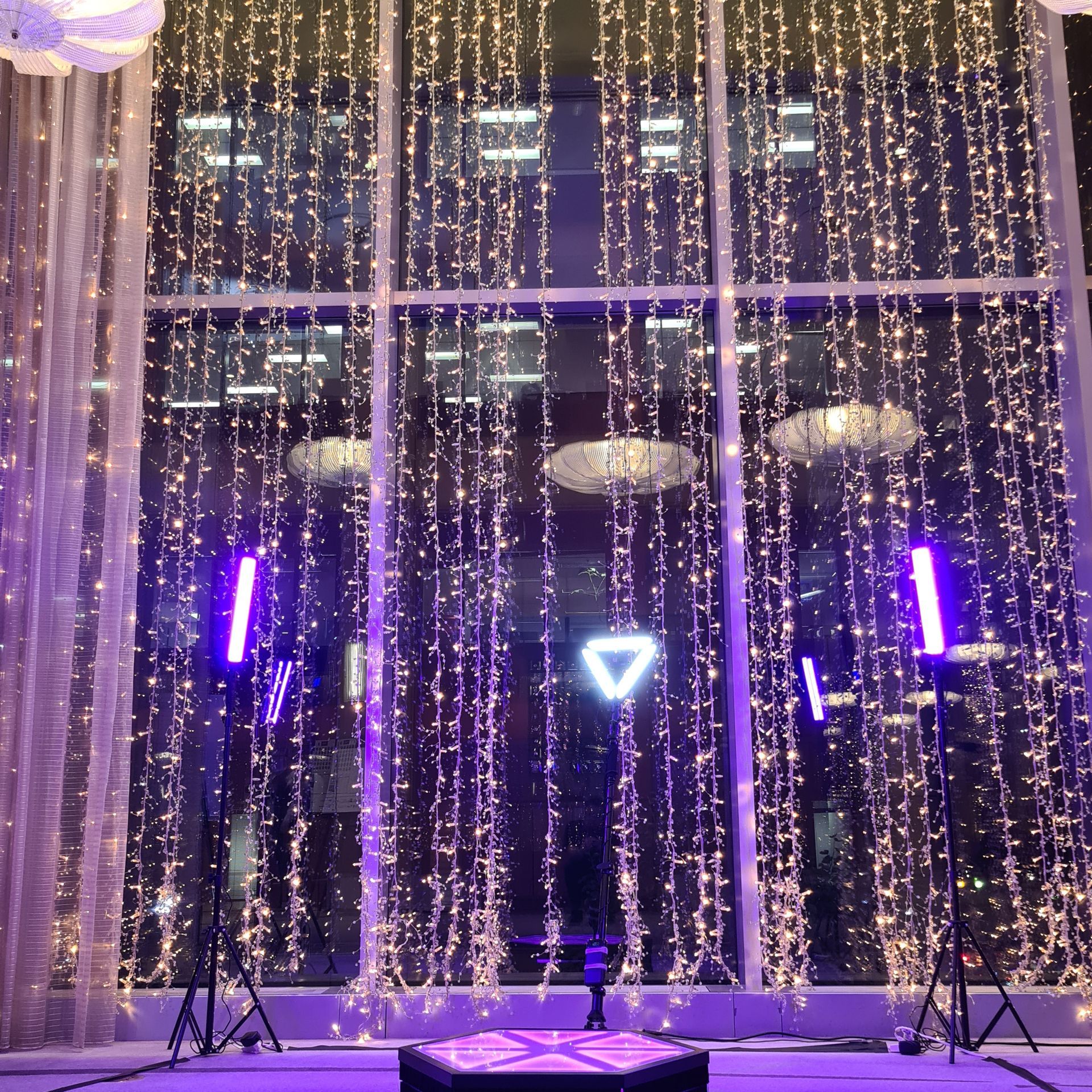Window display with string lights, purple stage lights, and a glowing triangle.