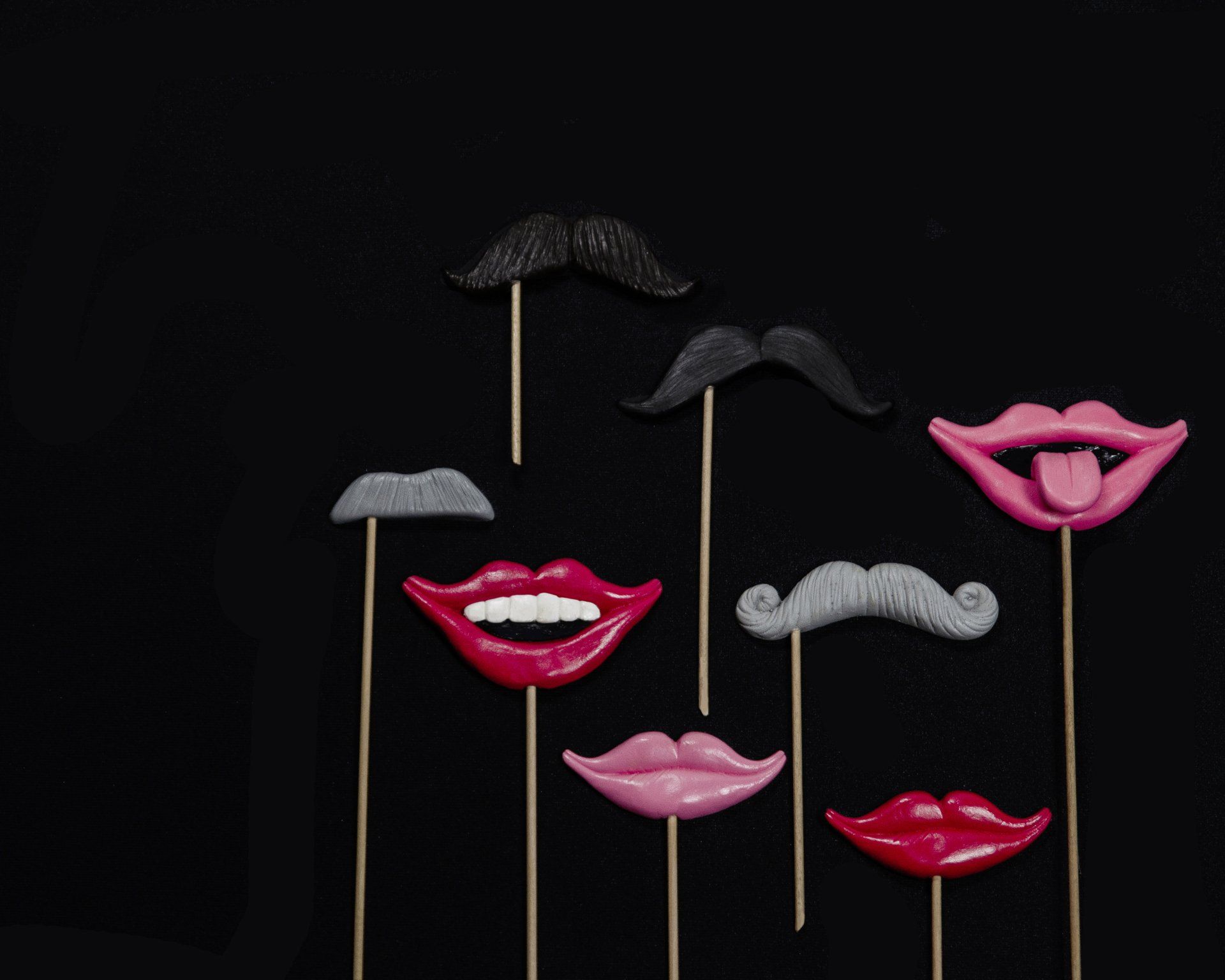 Mustaches and lips on sticks, photo booth props against a black backdrop.