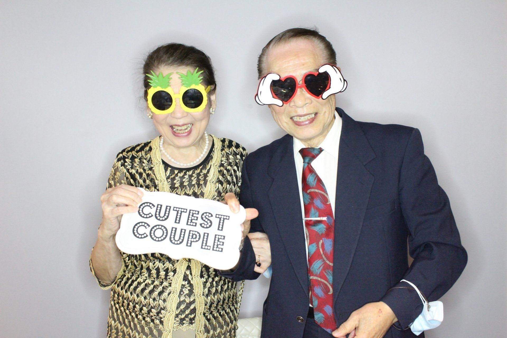 Couple wearing novelty glasses, smiling, holding 