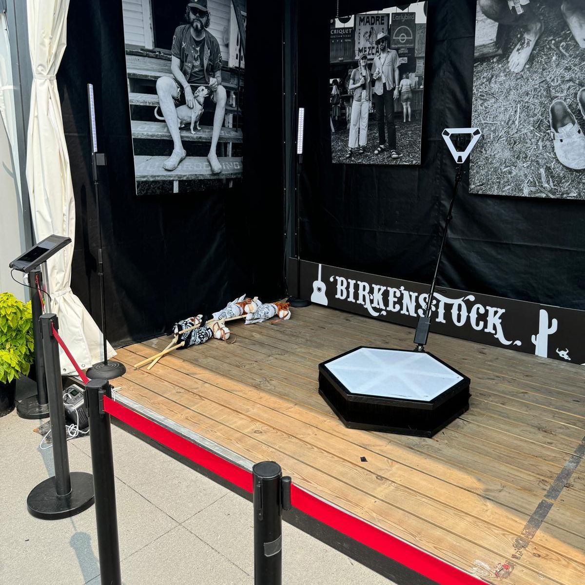 Photo booth for Birkenstock with red rope barrier. Dark backdrop with photos and a rotating platform.