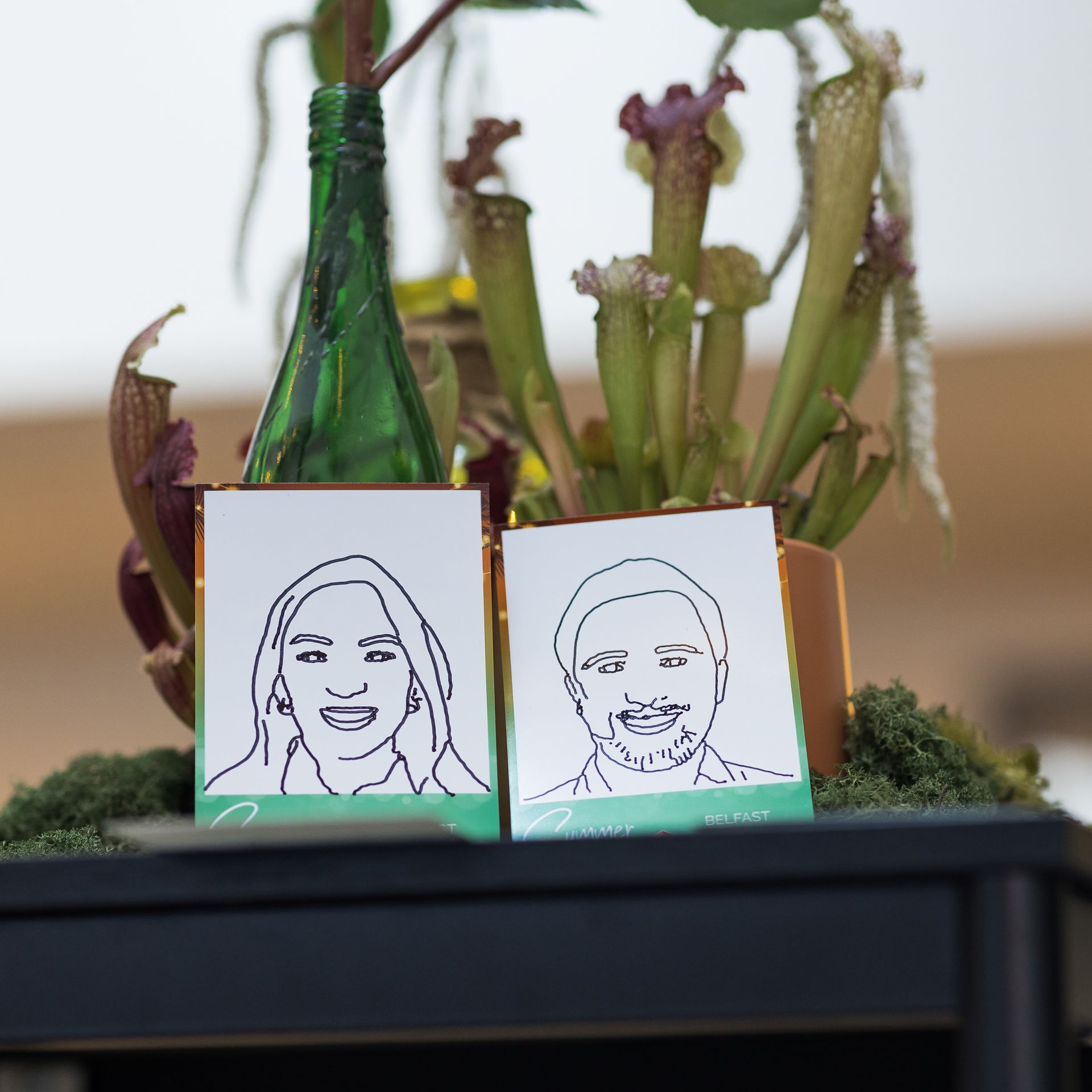 Cards with line drawings of two people in front of potted carnivorous plants and green bottle.