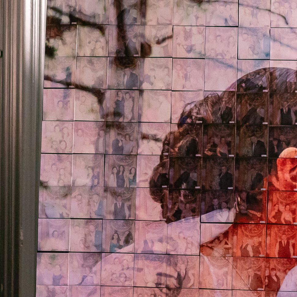 Mosaic wall art; person's profile in front of outdoor scenes. Blocks of images form larger picture.