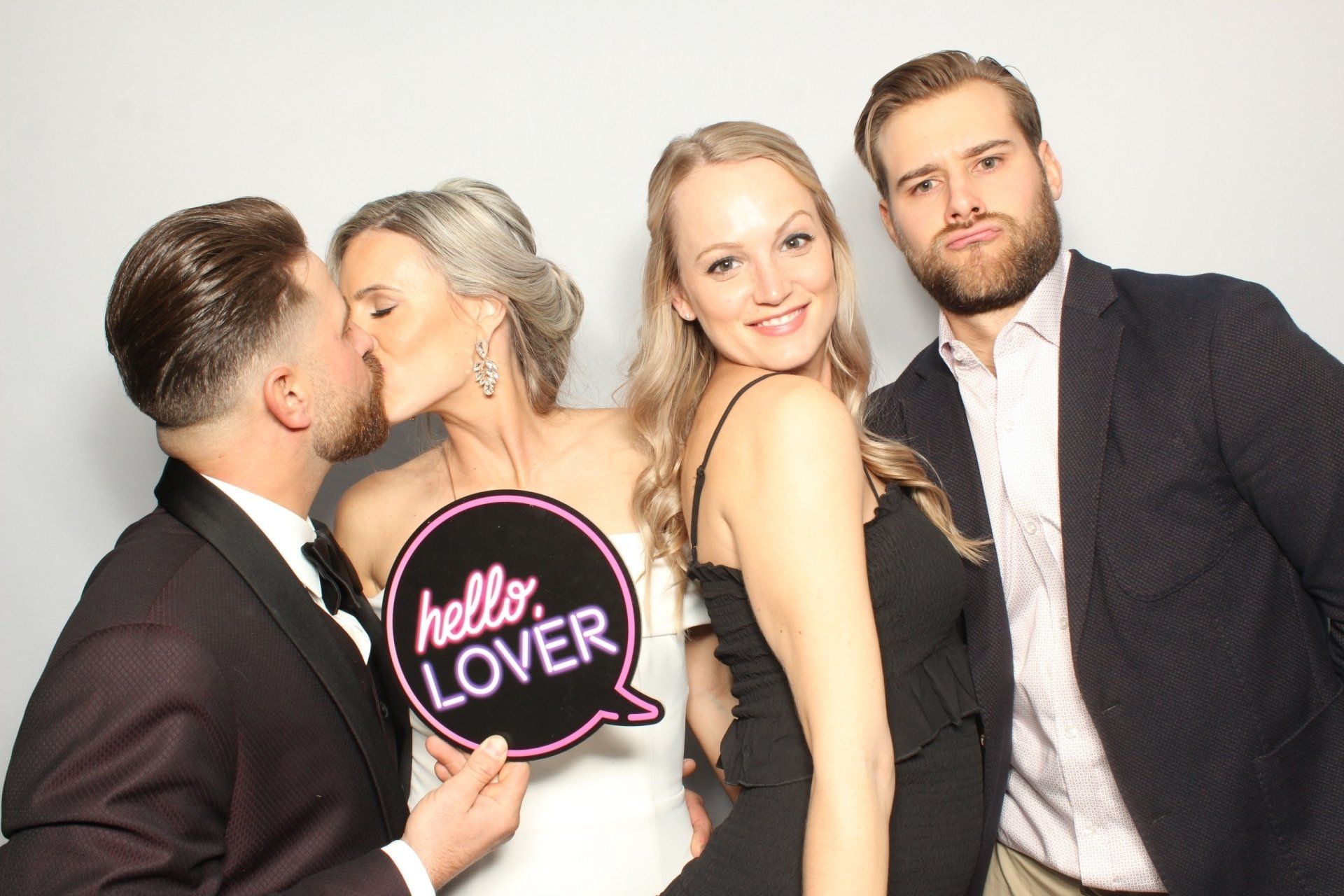 Four people posing for a photo booth. One person holds a