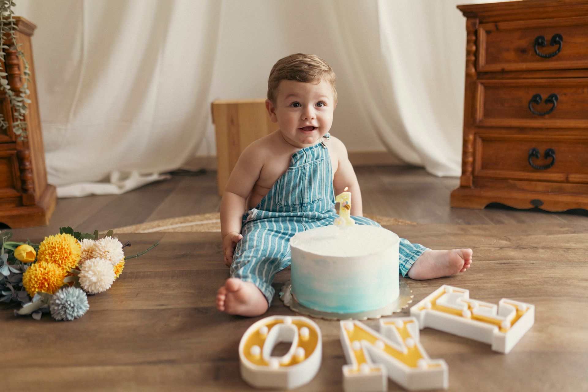 Un bambino con una tuta a righe blu è seduto vicino a una torta con le lettere