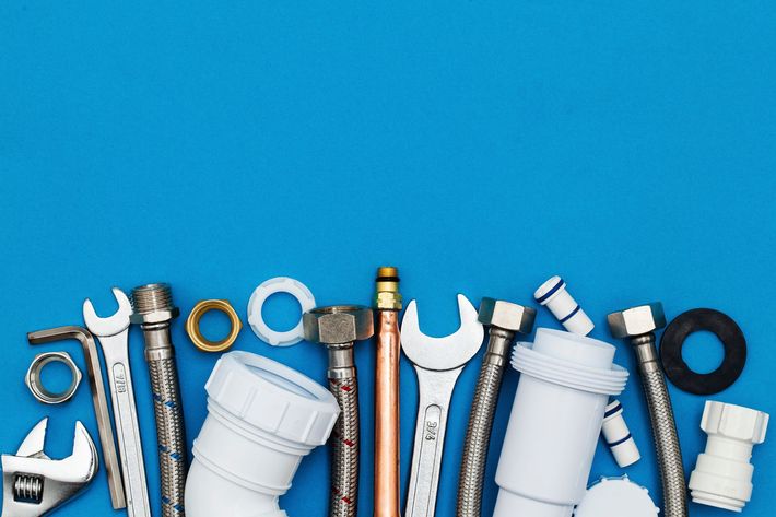 Assorted plumbing tools and pipe fittings on a blue background Assorted plumbing tools and pipe fittings on a blue background