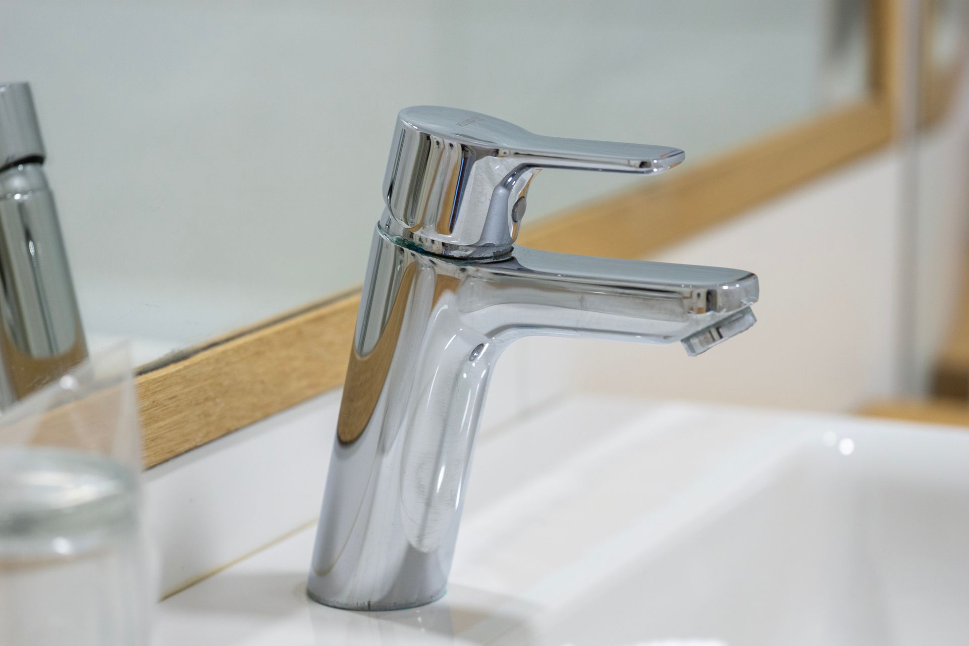 Chrome bathroom faucet over white sink, with a mirror in the background Chrome bathroom faucet over white sink, with a mirror in the background