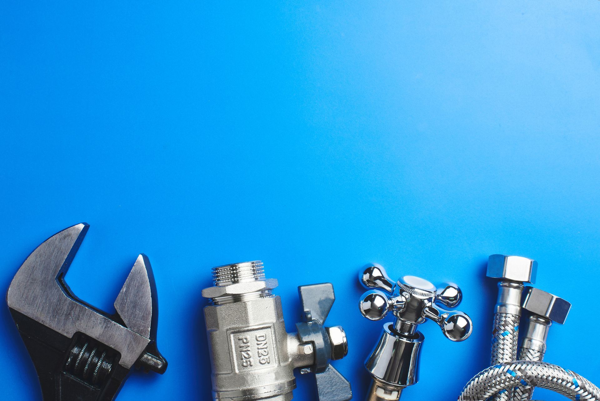 Assorted metal plumbing tools and fittings on a bright blue background Assorted metal plumbing tools and fittings on a bright blue background