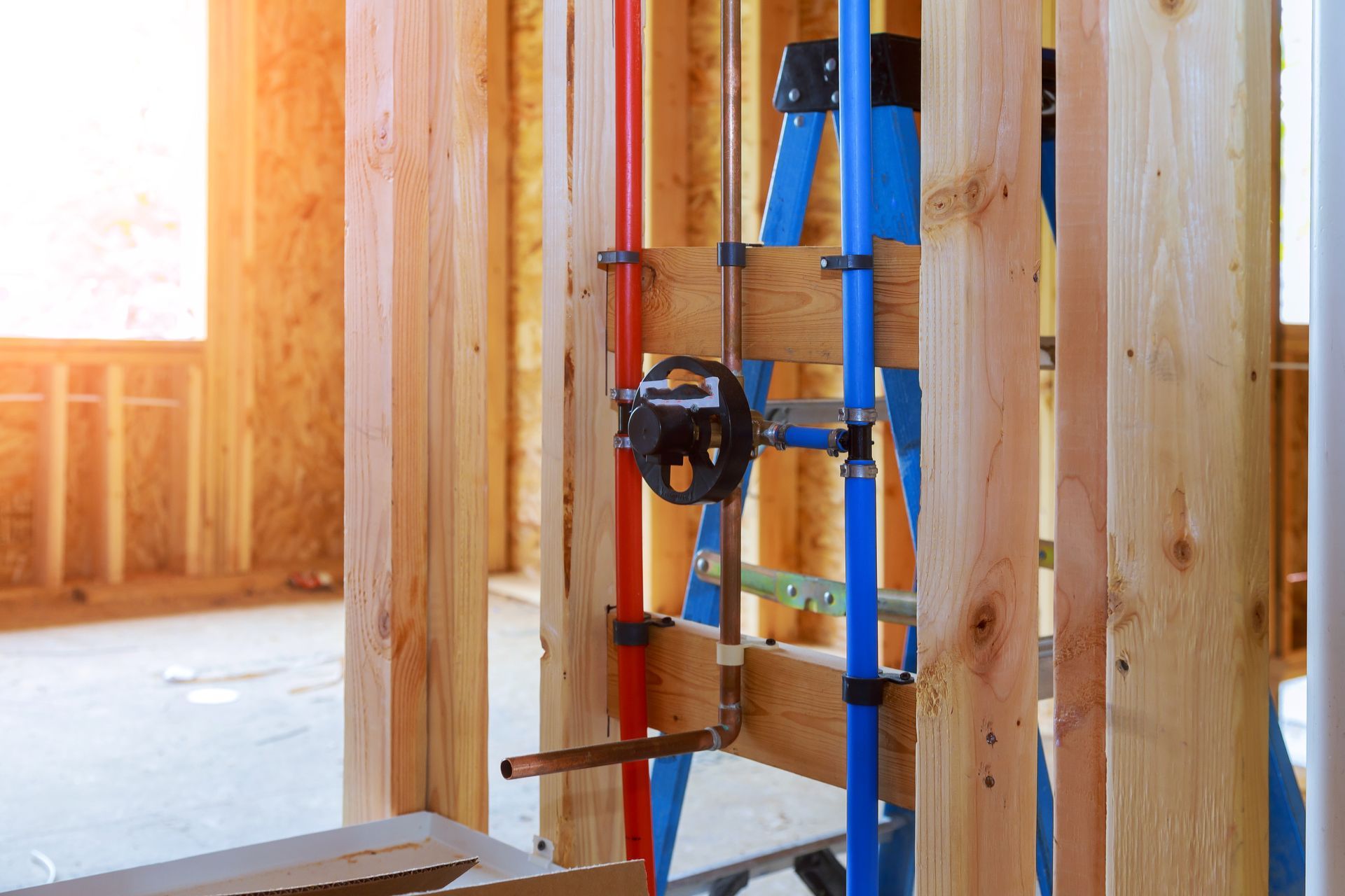 Blue ladder with tools inside a framed wooden house under construction