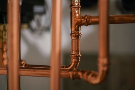 Close-up of copper pipes and fittings in a plumbing system against a blurred background