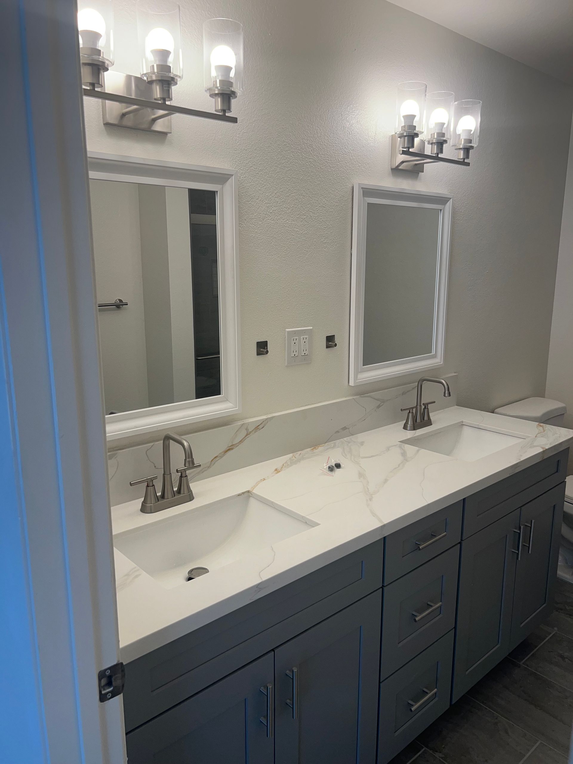 Modern bathroom vanity with double sinks, mirrors, and wall sconces, remodeled by Kearney Restorations