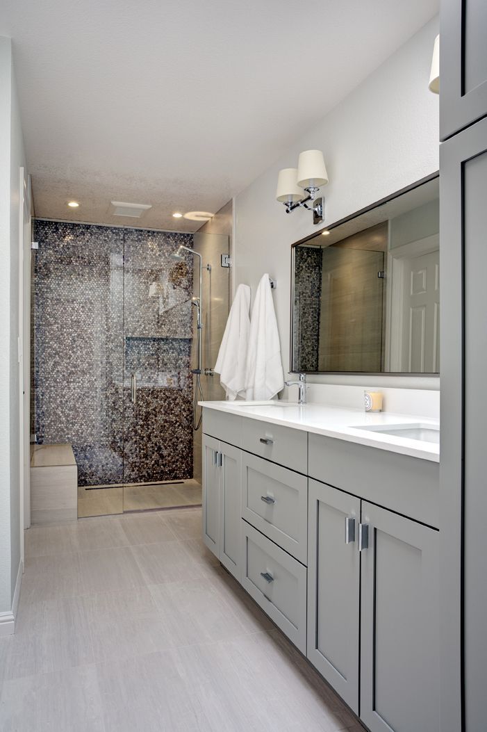 Modern bathroom with double vanity, large mirror, and tiled shower at the back