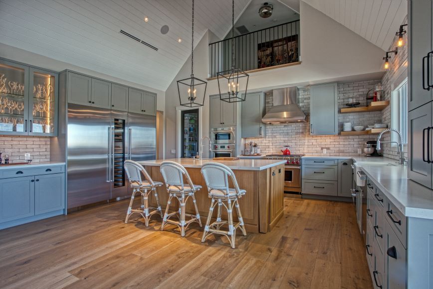 Modern kitchen with stainless steel appliances, island seating, and vaulted white ceilings