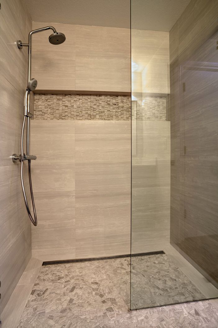 Modern walk-in shower with glass partition, rainfall showerhead, and beige tile walls.